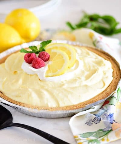 lemonade pie in a graham cracker crust and topped with lemon slices and fresh raspberries