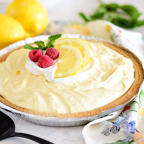 lemonade pie in a graham cracker crust and topped with lemon slices and fresh raspberries