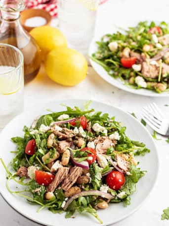 two plates of salad with a fresh lemon on the counter