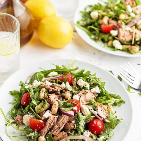 two plates of salad with a fresh lemon on the counter