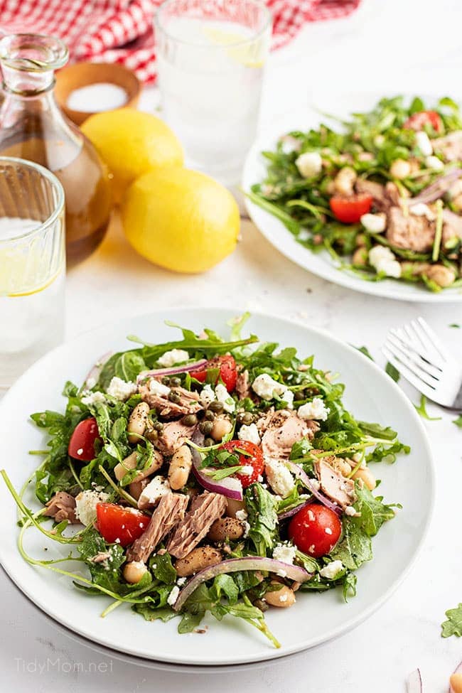 two plates of salad with a fresh lemon on the counter