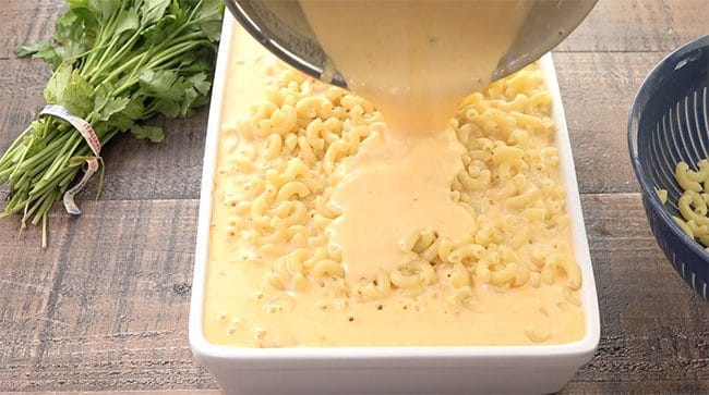 pouring cheese over mac 'n cheese 