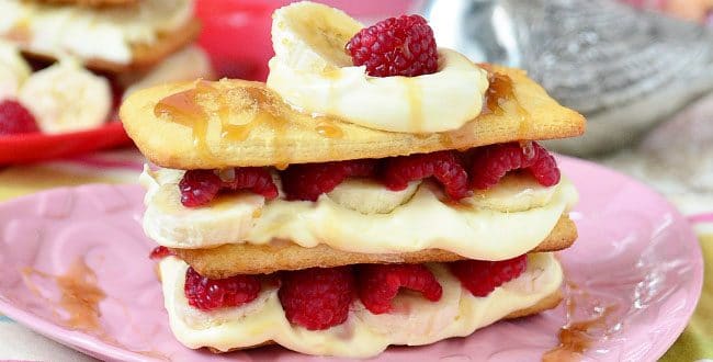 Napoleon dessert recipe with raspberries, bananas and caramel sauce on pink plate