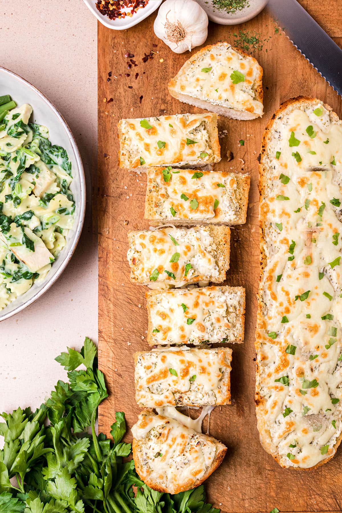 2 loaves of fresh baked cheesy garlic bread on a cutting board