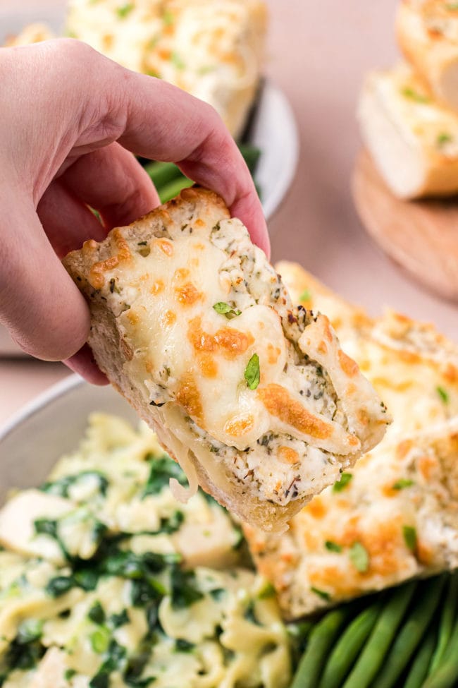 hand holding a slice of Garlic Cheese Bread
