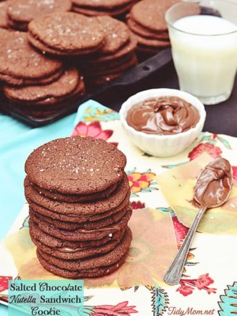 Salted Chocolate Nutella Sandwich Cookies recipe is the perfect balance of chocolate and Nutella all wrapped up in a chewy cookie. Take two dark chocolate crispy oat cookies and smear a little Nutella between the two, with a dusting of sea salt and you’ve got yourself one heck of a good sandwich. Print the full recipe at TidyMom.net #cookies #nutella