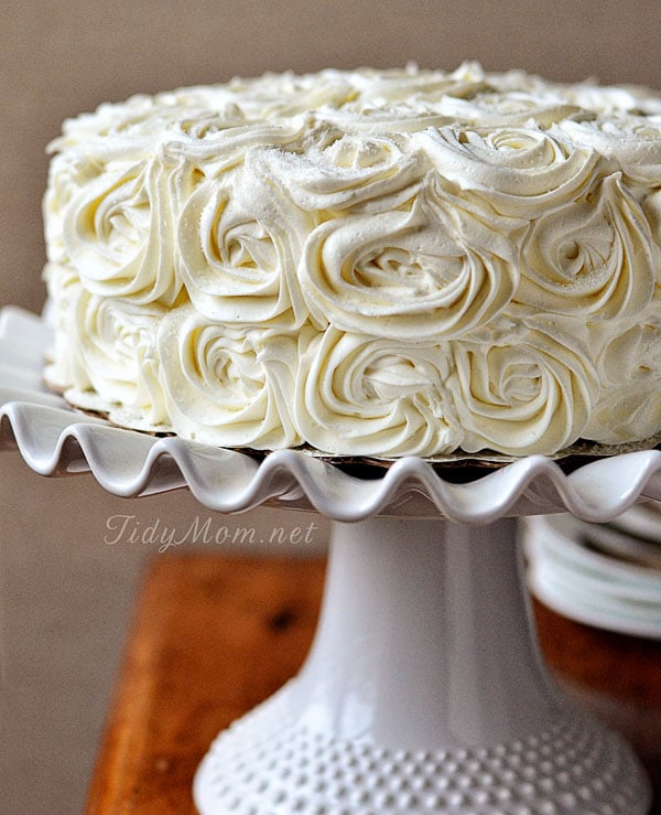 cake with white frosting on a platter decorated with frosting rosettes