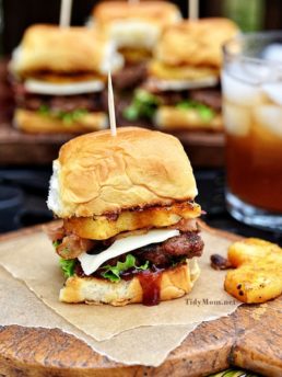 Fire up the grill this summer for this mini Hawaiian burger recipe. Aloha BBQ Sliders are flavored with barbecue sauce and served on sweet rolls with cheese, pineapple and bacon.