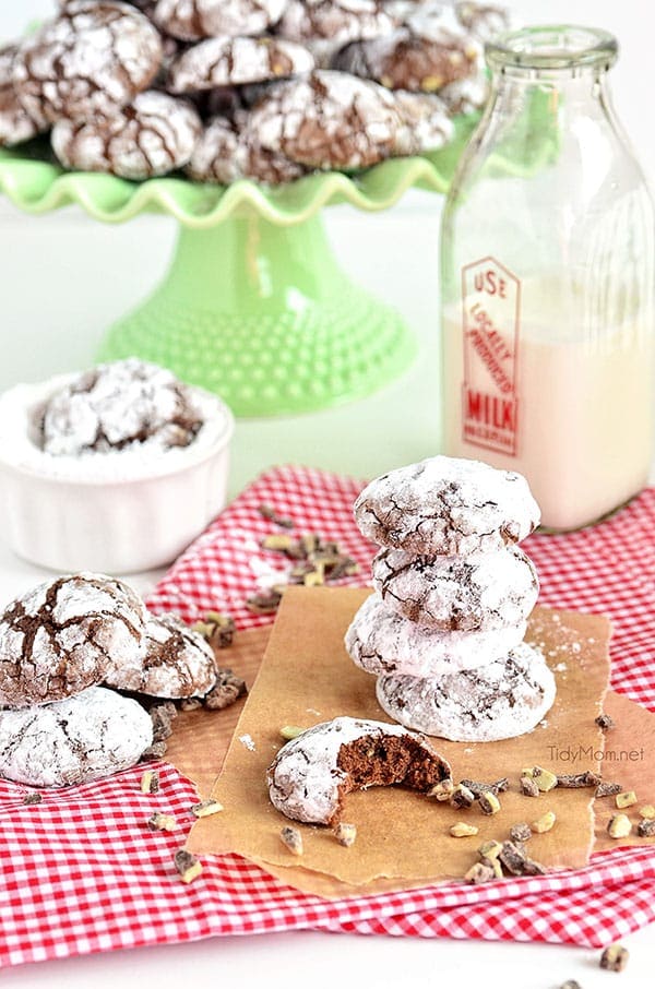 chocolate crinkle cookies on a green cake stand with a red and white napkin and a bottle of milk