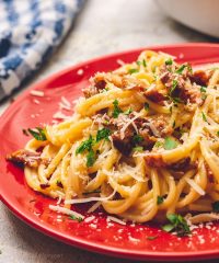 Delicious classic Bacon Carbonara on a red plate