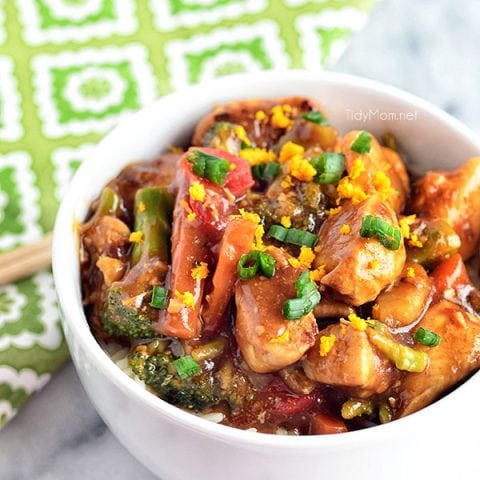 orange chicken in a white bowl with a green napkin