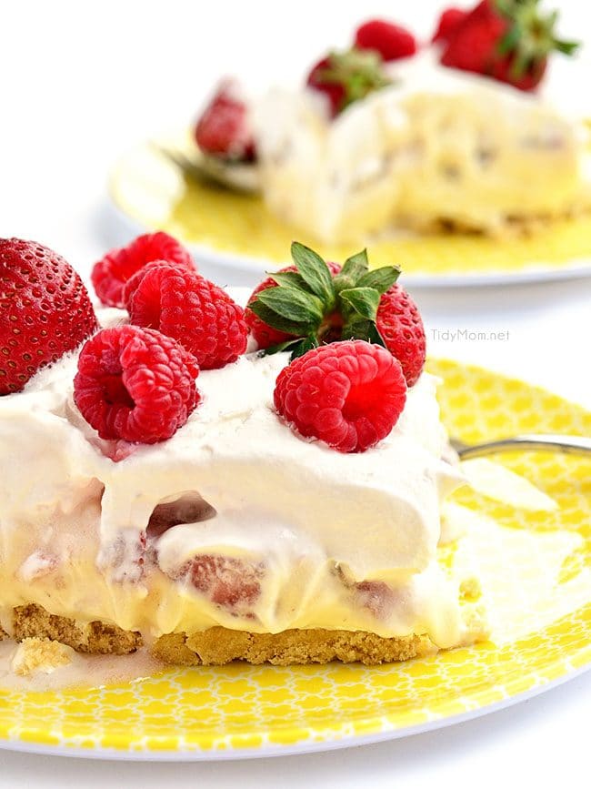 no-bake strawberry cheesecake dessert topped with fresh berries on yellow plates
