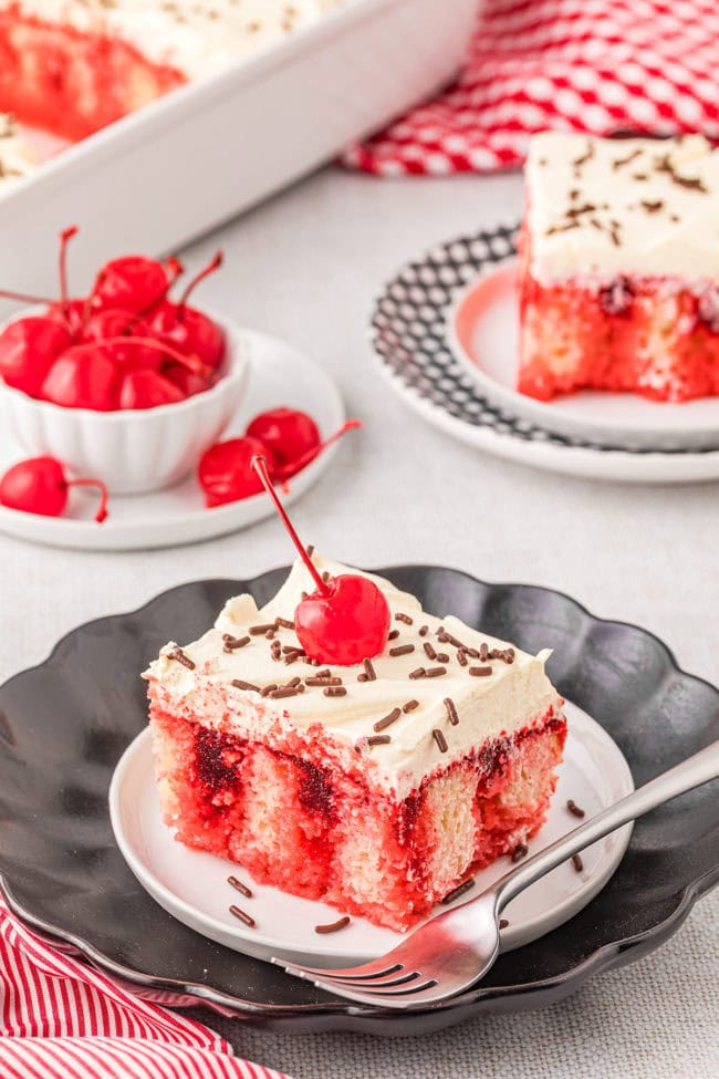 cherry jello poke cake with maraschino cherry and jimmies on top
