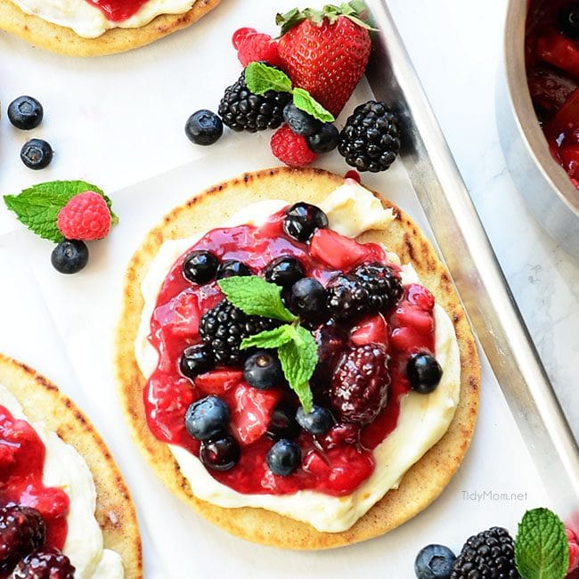 Berry Breakfast pizza tastes as good as it looks! It's impossible to resist the toasted flatbread crust, rich orange mascarpone layer and glossy berry topping. It's so convenient to prepare the night before and serve the next morning, or any time of day! Full recipe at TidyMom.net