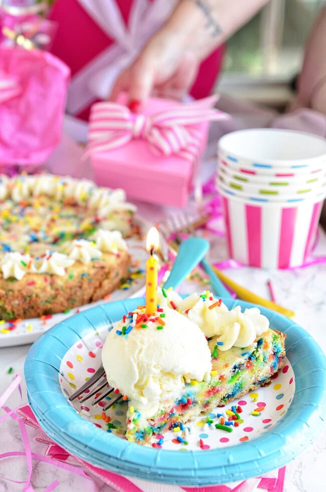 birthday cookie cake on a plate with a scoop of ice cream and a candle