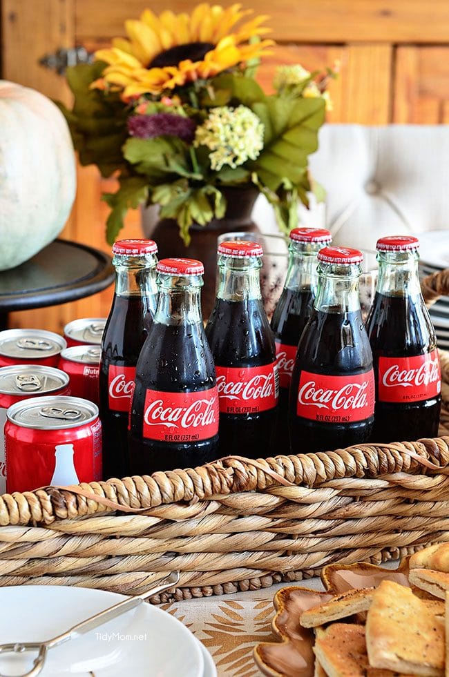 Coca-Cola cans and bottles in a basket on a table