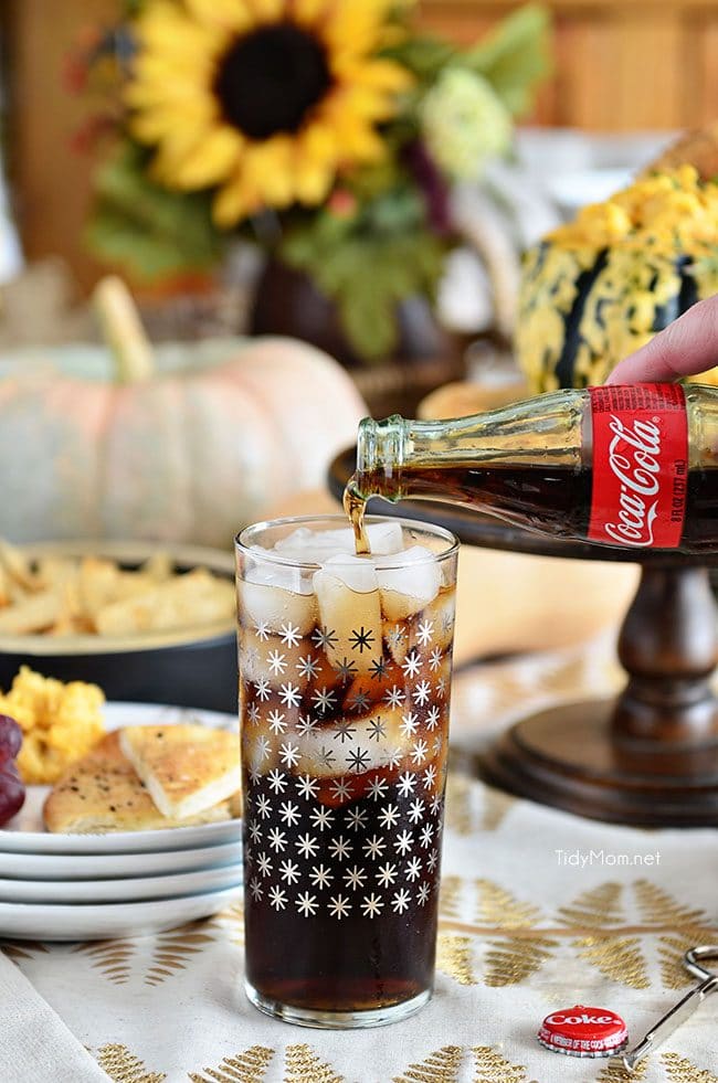 Pouring a bottle of Coca-Cola into a glass with ice