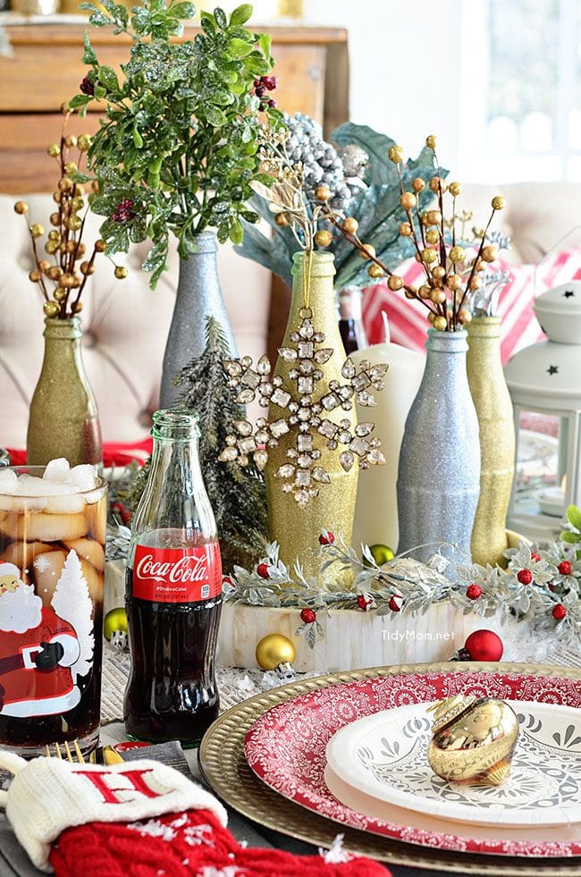 Use empty Cocoa Cola bottles as a pretty holiday table centerpiece. Just paint with glitter spray paint and add some holiday florals, and arrange on a tray. Easy and costs almost nothing! details at TidyMom.net