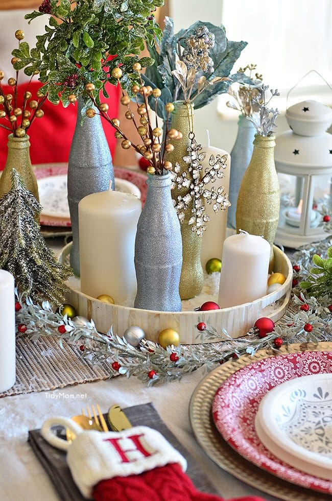 Use empty Cocoa Cola bottles as a pretty holiday table centerpiece. Just paint with glitter spray paint and add some holiday florals, and arrange on a tray. Easy and costs almost nothing! details at TidyMom.net