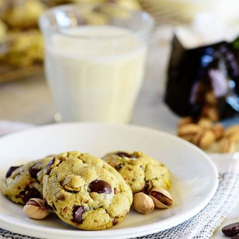Pistachio cookies on a plate with a glass of milk
