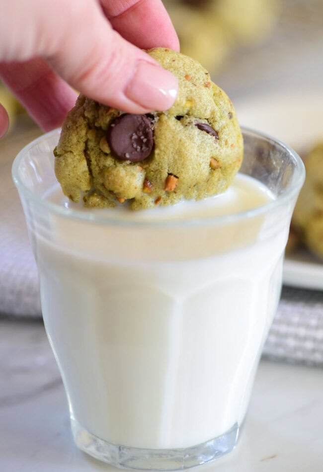 dunking a green cookie in a glass of milk