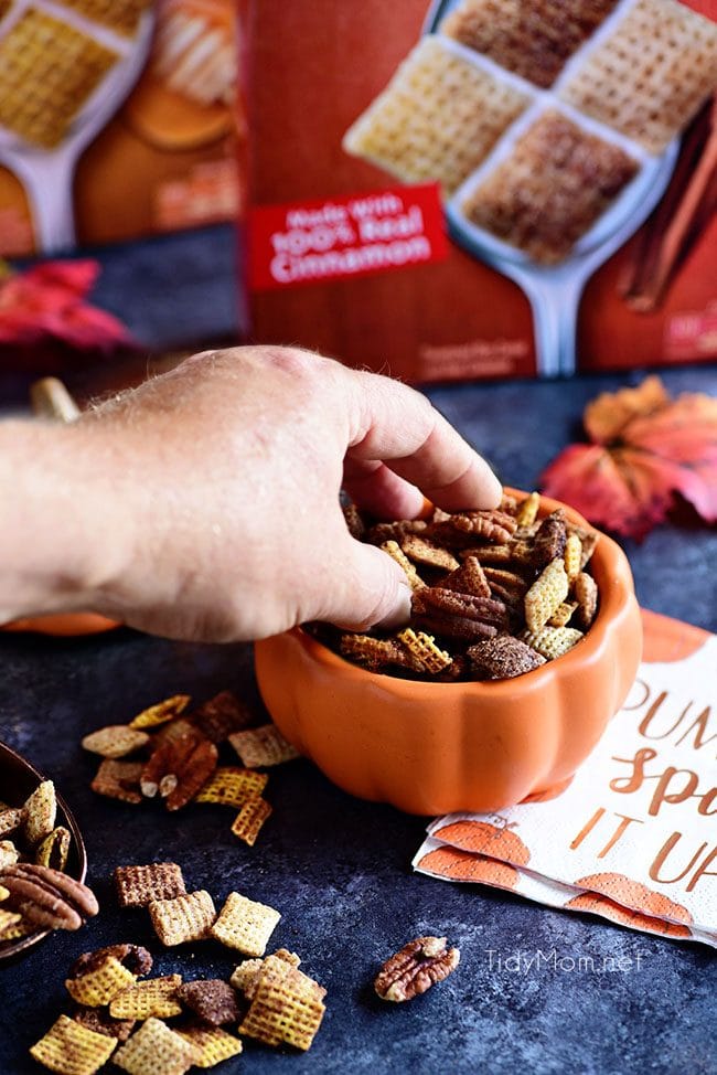 grabbing a handful of chex mix out of bowl