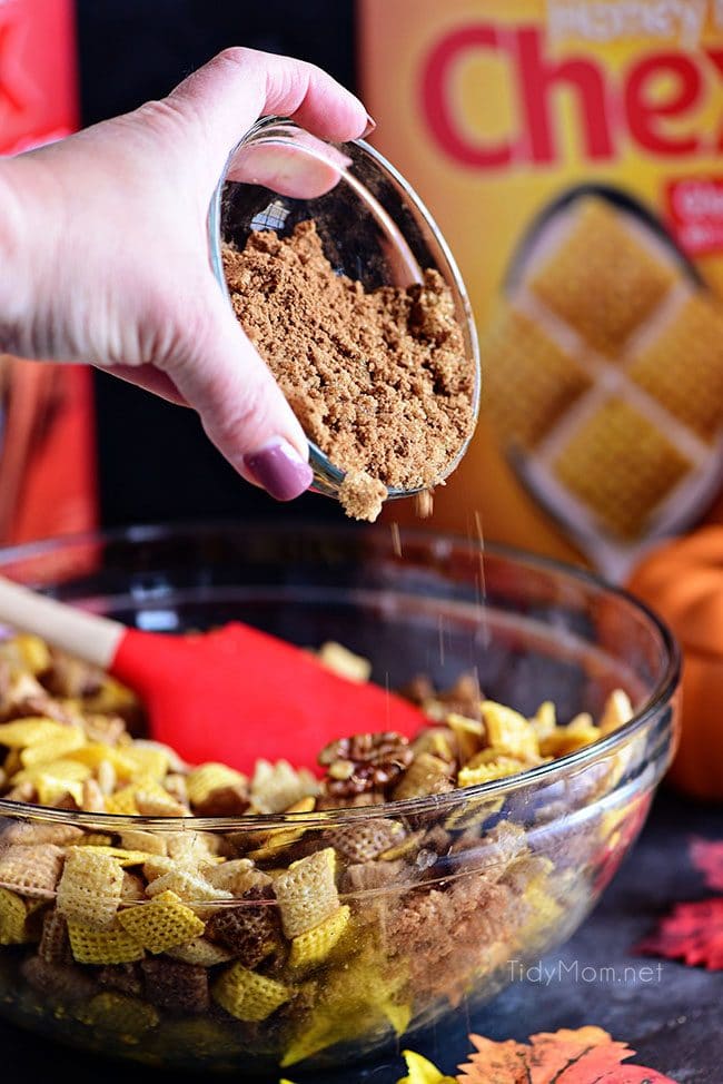 Adding sugar and spice to make Pumpkin Spice Chex Mix on pan