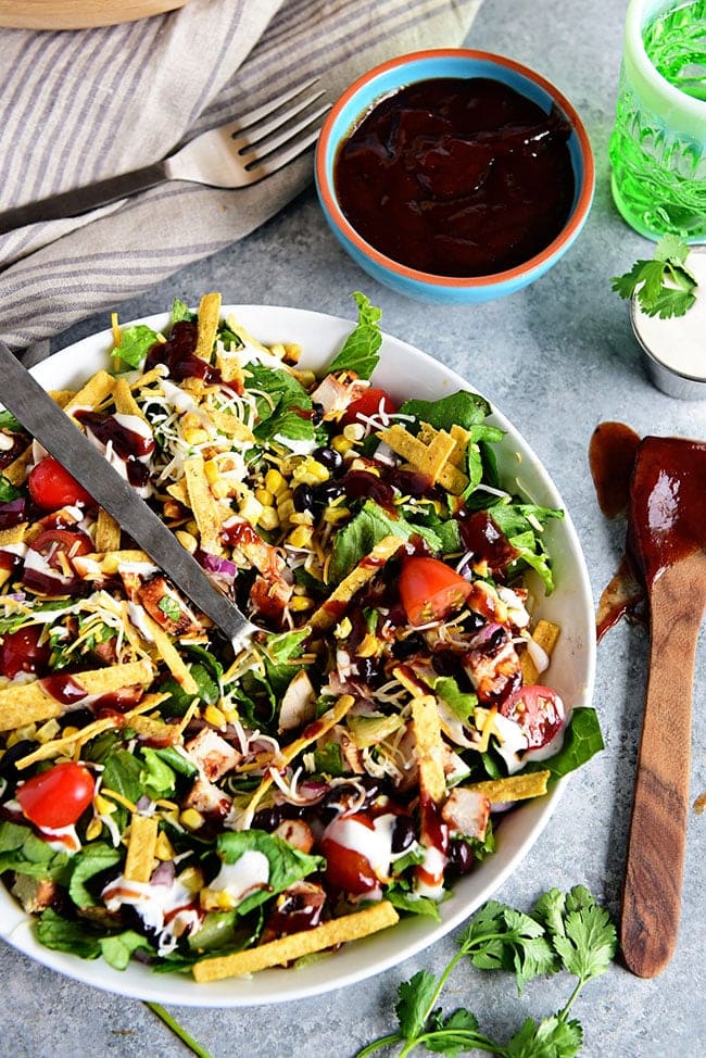 This BBQ Chicken Salad is super easy, can even be made with leftovers and it's off the hook delicious! Grilled corn and lime crema really make it sing!  If you were a fan of Panera's BBQ Chicken Salad, you're going to love this copycat salad you can make in 15 minutes or less at home! Print the full recipe at TidyMom.net