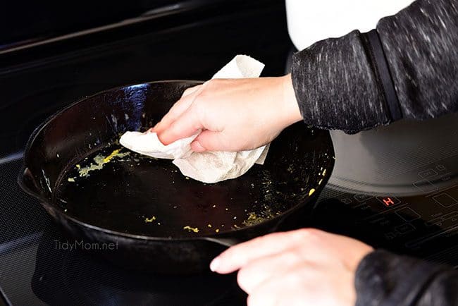how to clean a cast iron skillet: Cleaning a cast iron skillet with a paper towel