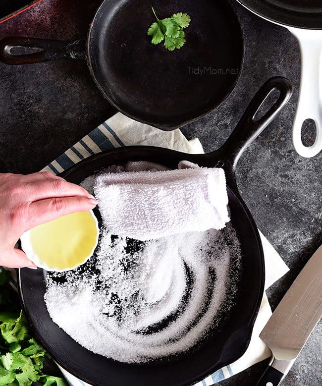 how to clean a cast iron skillet: pouring oil into a cast iron skillet with salt to clean