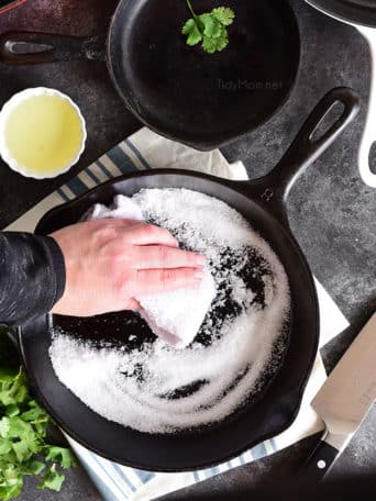cast iron skillet being cleaned with salt and oil