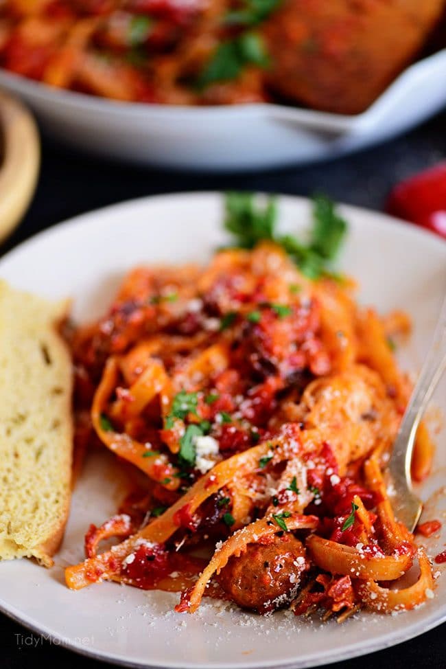 Delicious Roasted Red Pepper Fettuccine with Smoked Sausage close up on white plate