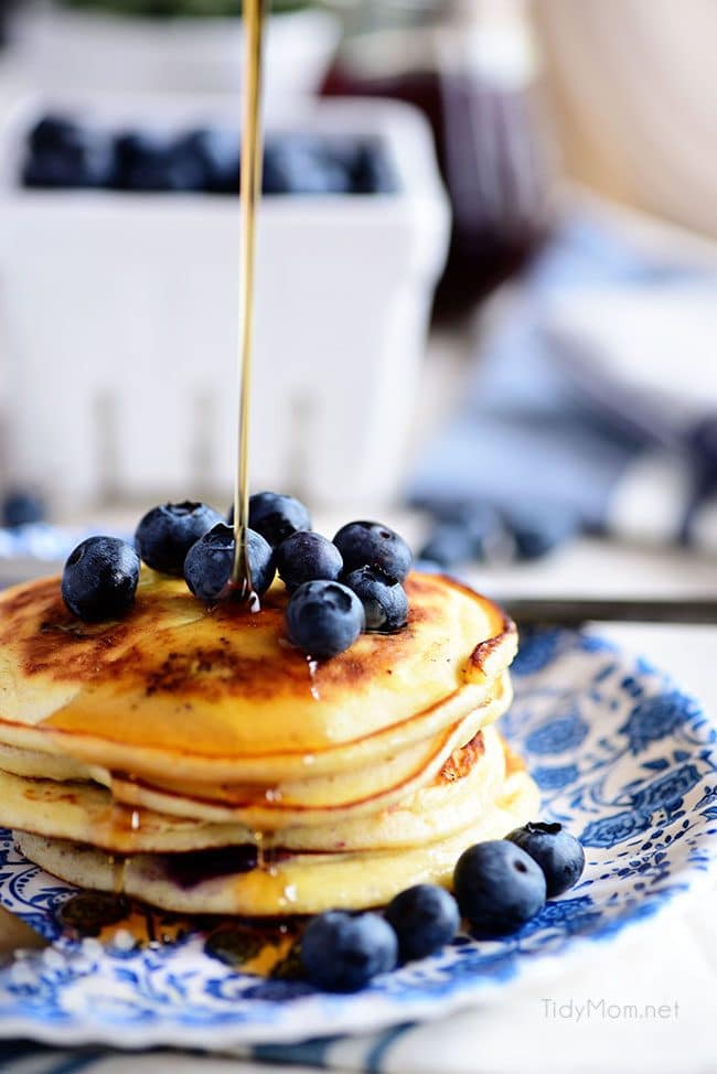 Pouring syrup on the Best Homemade Blueberry Pancakes. 