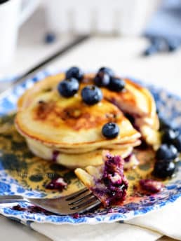 a stack of blueberry pancakes on a blue floral plate