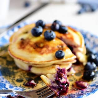 a stack of blueberry pancakes on a blue floral plate