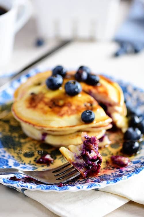 a stack of blueberry pancakes on a blue floral plate.