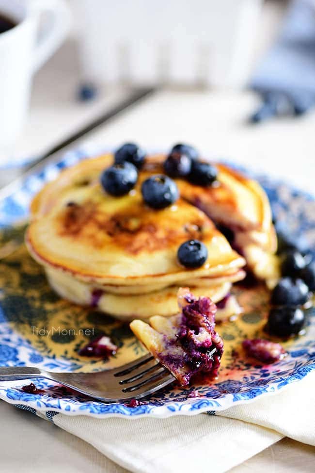 a stack of blueberry pancakes on a blue floral plate