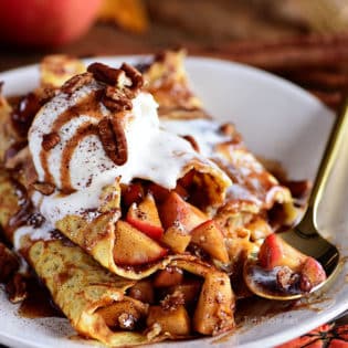 Apple Pie Crepes are thin french pancakes filled with a gooey caramel apple compote and toasted cinnamon pecans. Top with ice cream for the perfect dessert crepes.