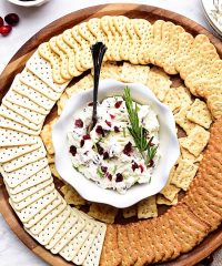 Cranberry Cream Cheese Dip with rosemary on a round tray with crackers
