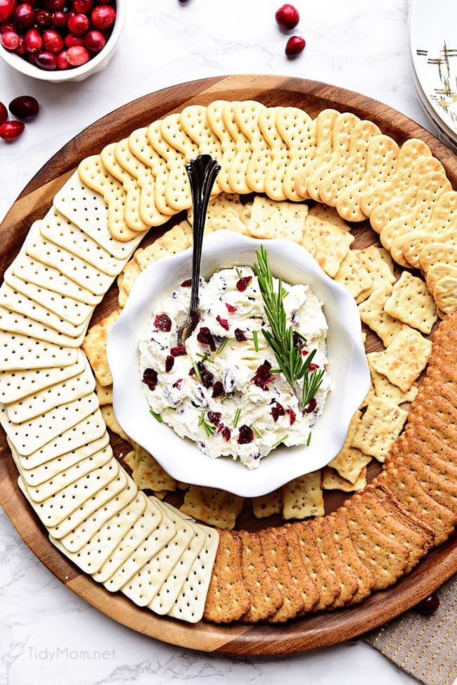 Cranberry Cream Cheese Dip with rosemary on a round tray with crackers