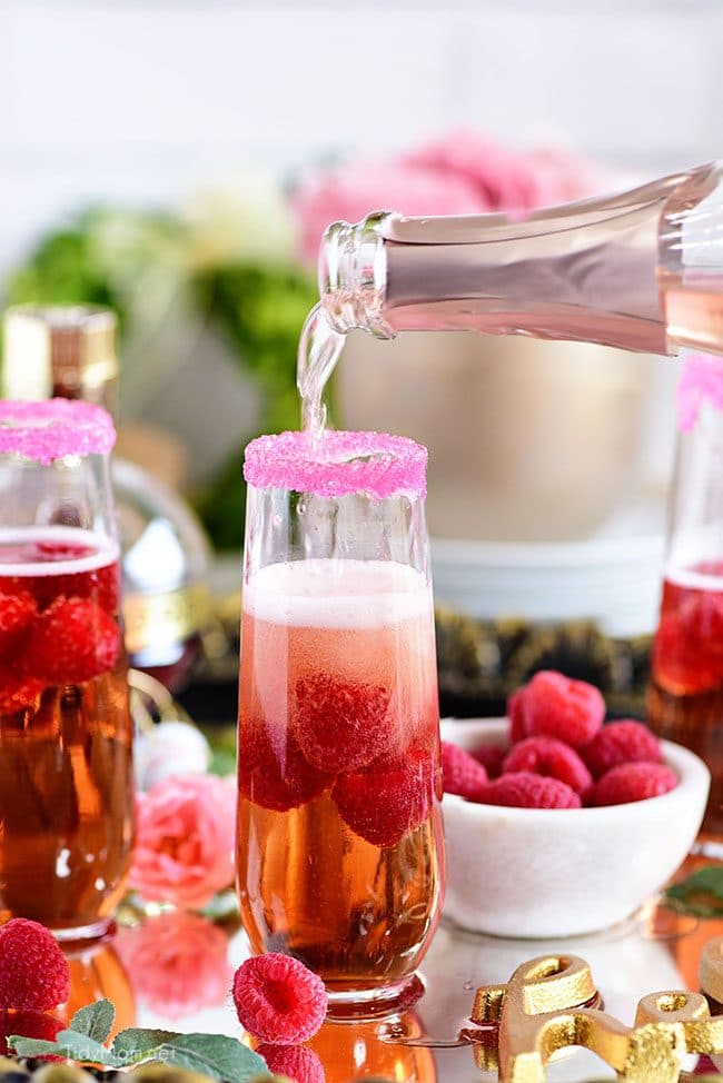 Pouring champagne for a Raspberry Kir Royale cocktail in champagne flute