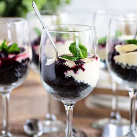 Cheesecake Parfaits with dark cherries in wine glasses