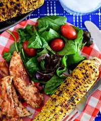 Chili Lime Corn On The Cob on dinner plate with BBQ chicken and salad