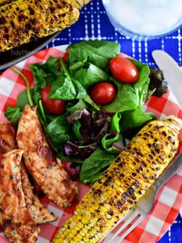 Chili Lime Corn On The Cob on dinner plate with BBQ chicken and salad