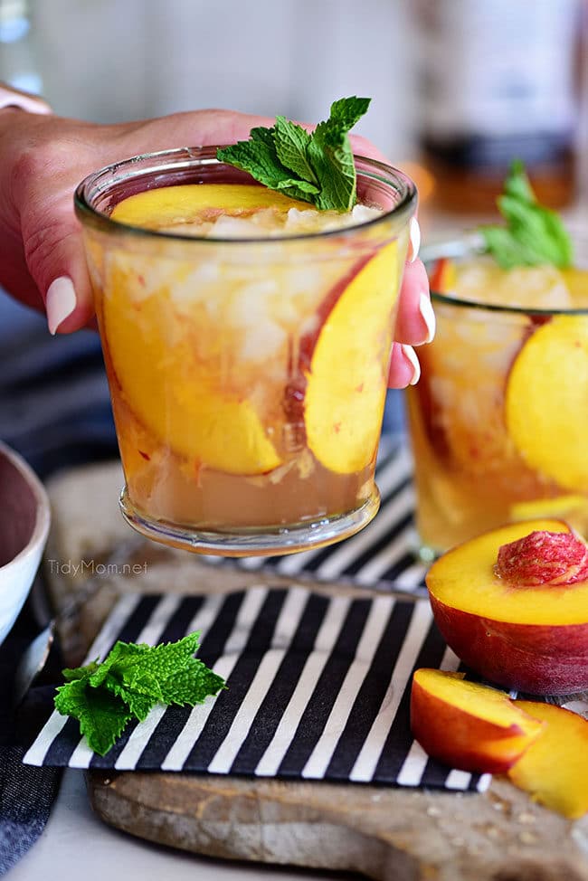 woman holding Ginger Peach Bourbon Smash cocktail