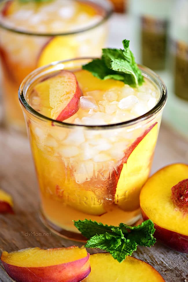 Ginger Peach Bourbon Smash cocktail on a board with a peach