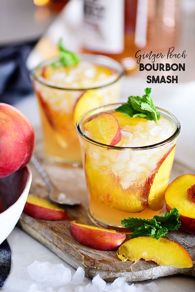 Ginger Peach Bourbon Smash cocktail on a board with fresh peach slices