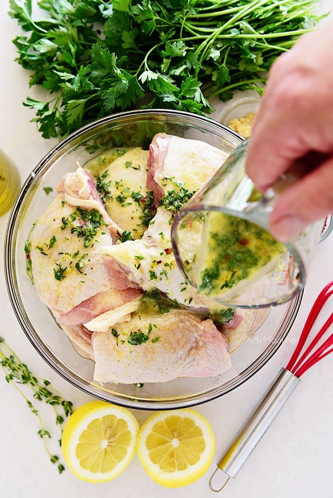 pouring easy lemon herb chicken marinade over raw chicken