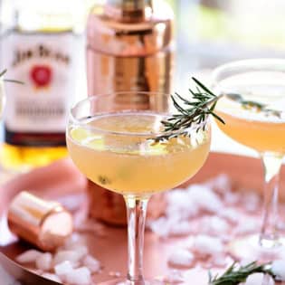 Bourbon Sour with smoked rosemary in coupe glasses