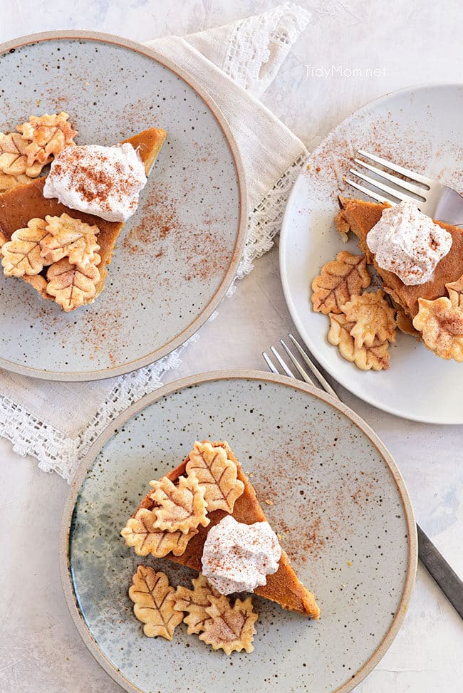 three pumpkin pie slices with cinnamon whipped cream